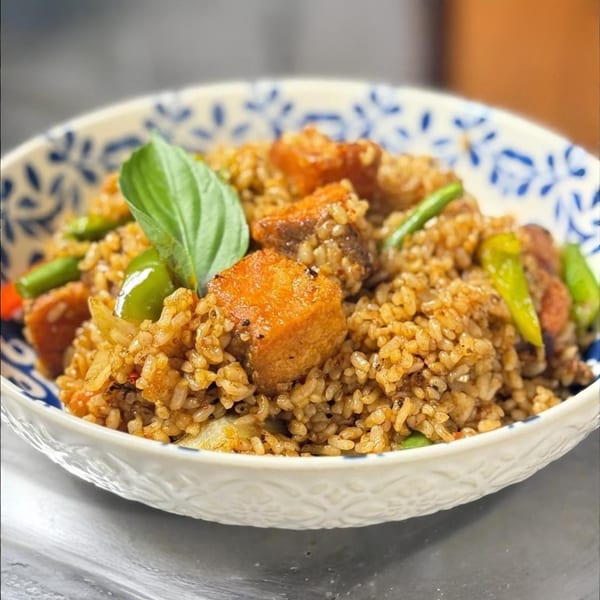 Thai fried rice with crispy salmon, green beans, and basil in a decorative bowl.