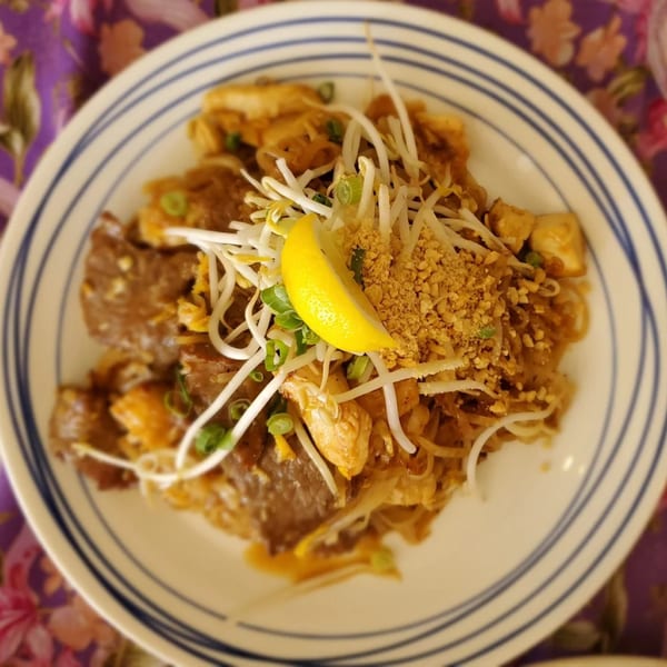 Thai Orchid's Pad See Ew with beef, chicken, tofu, bean sprouts, peanuts, and a lemon wedge.