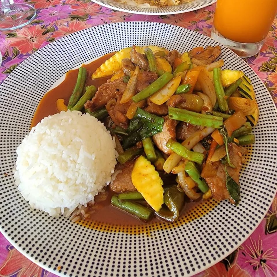 Thai stir-fry with meat, green beans, and pineapple, served with white rice on a patterned plate.