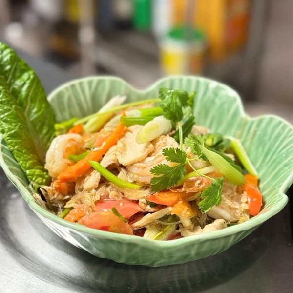 Thai glass noodle salad with chicken, shrimp, vegetables, and cilantro in a green bowl.